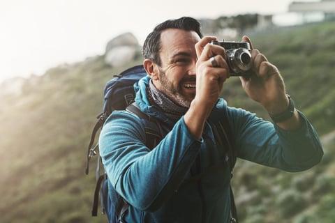 Shot of a middle aged man taking pictures with his camera in the mountains