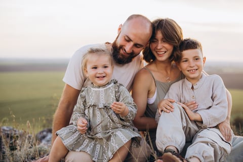 A joyful family with parents and young children spending time together in a tranquil field