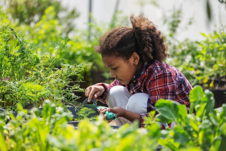 A focused young child works the soil in a lush garden, carefully tending plants with a small tool