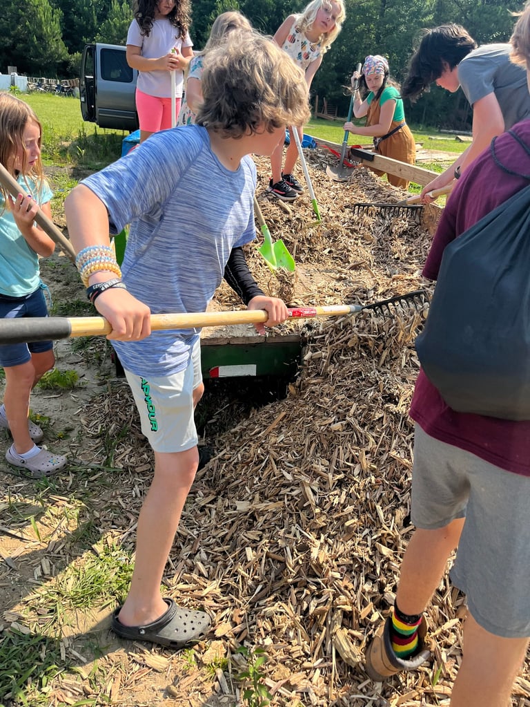 Group of people working with mulch and tools at an outdoor community garden or landscaping event